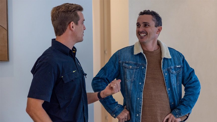 Two men talking to each other inside a modern office setting.