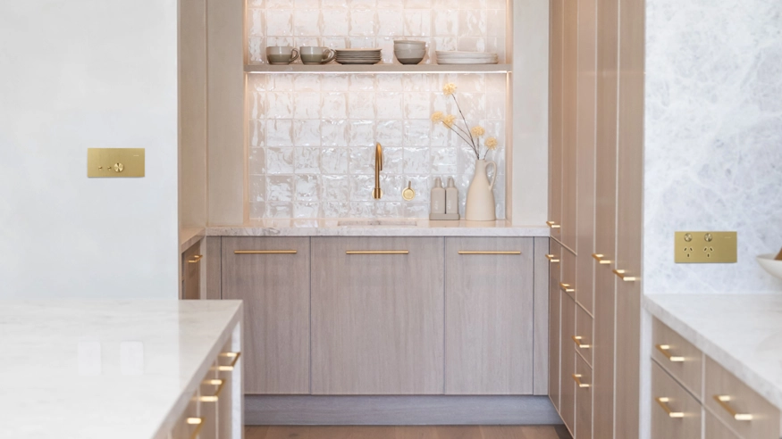 A modern kitchen featuring premium new range of electrical switches and power points complemented on white cabinets with elegant gold hardware.