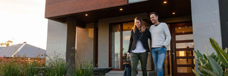 A happy couple posing outside their sleek modern home.