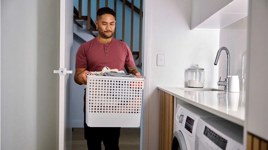 A man walks into a laundry room with automatic smart home activated lights.