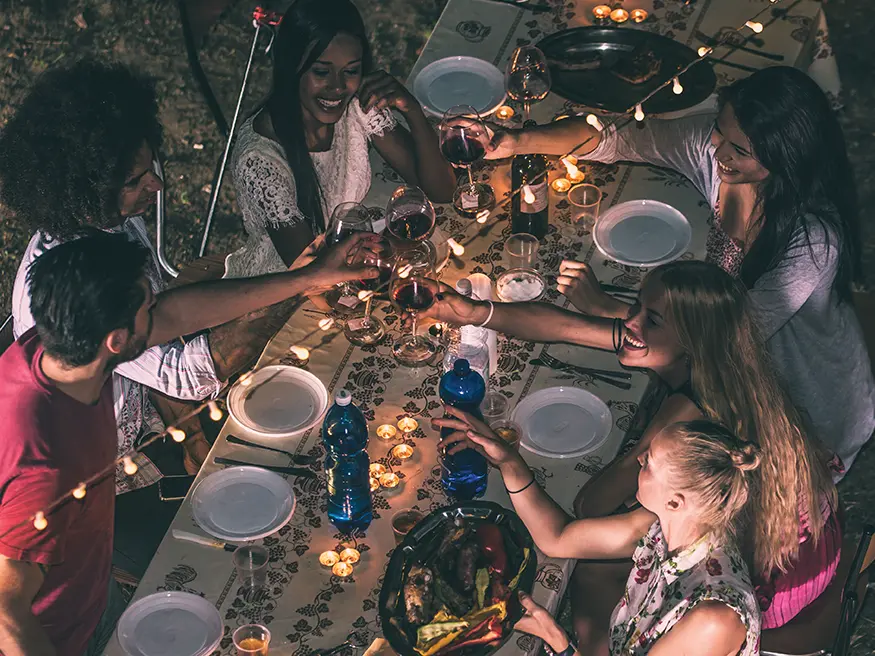 A cheerful gathering of people clinking glasses in celebration at a dinner table.