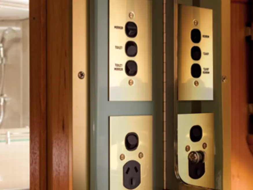 Two panels of metal switch plates with labeled black switches and outlets; left has extra outlet, right has coaxial port.