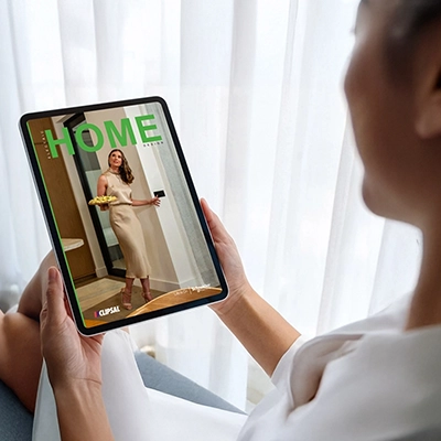 A woman holding a tablet browsing the Electric Home Design digital magazine.