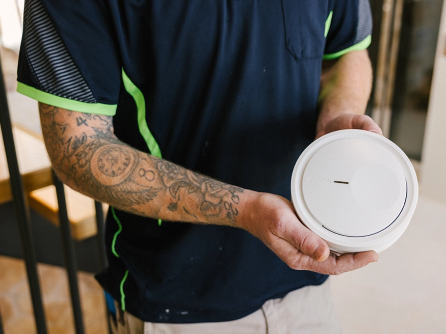 An electrician holding a Clipsal Fire Tek Smoke Alarm.