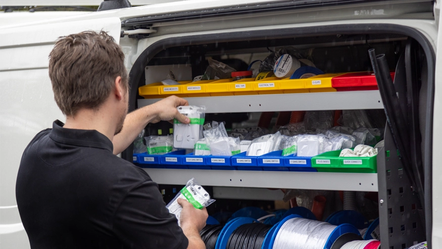 A man is inspecting the quality of items at the back of the van.