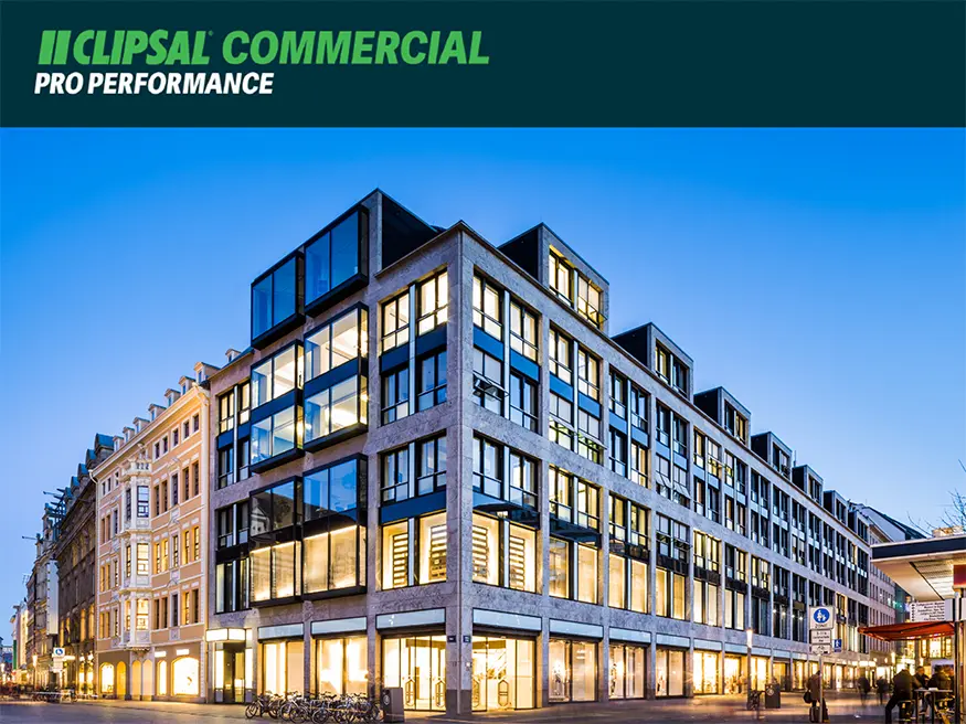 Modern multi-story commercial building with glass facade illuminated at dusk.