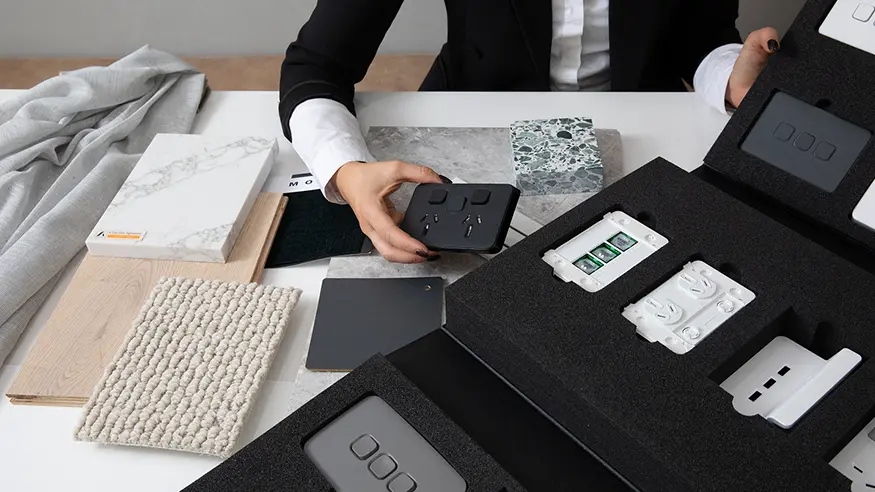 A professional builder inspects a display case of Clipsal Iconic switches and sockets.