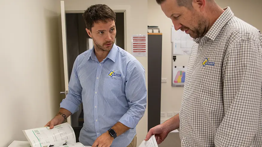 Two people flipping through the Schneider Electric product catalouge.