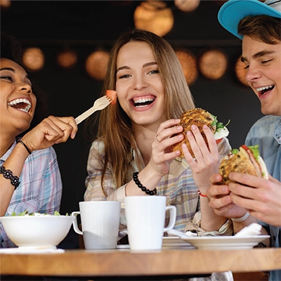 Three teenagers converse and have dinner together.